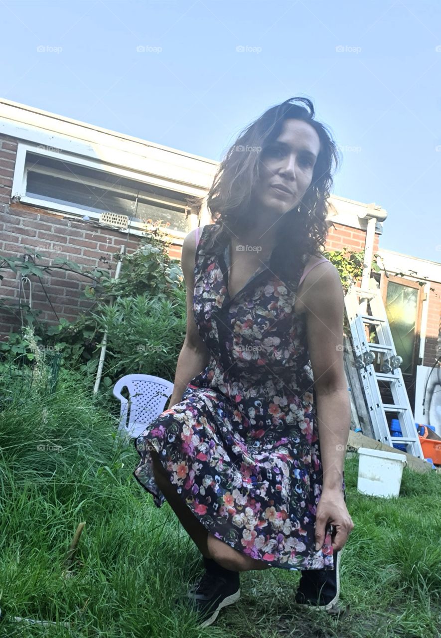 On the grass taking a picture of a woman squatting down.