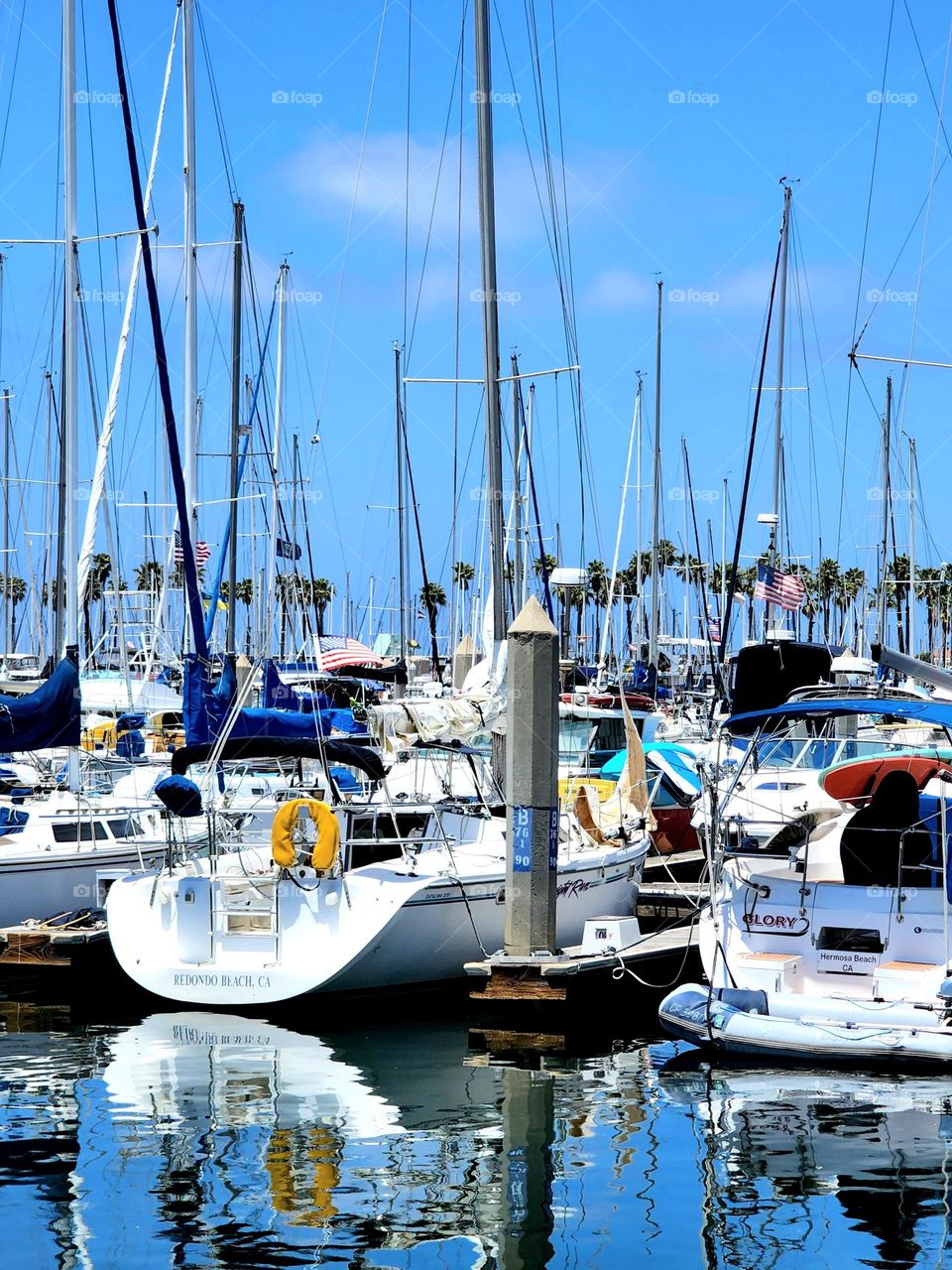 Sailboats and power boats are docked in a marina one calm and beautiful morning