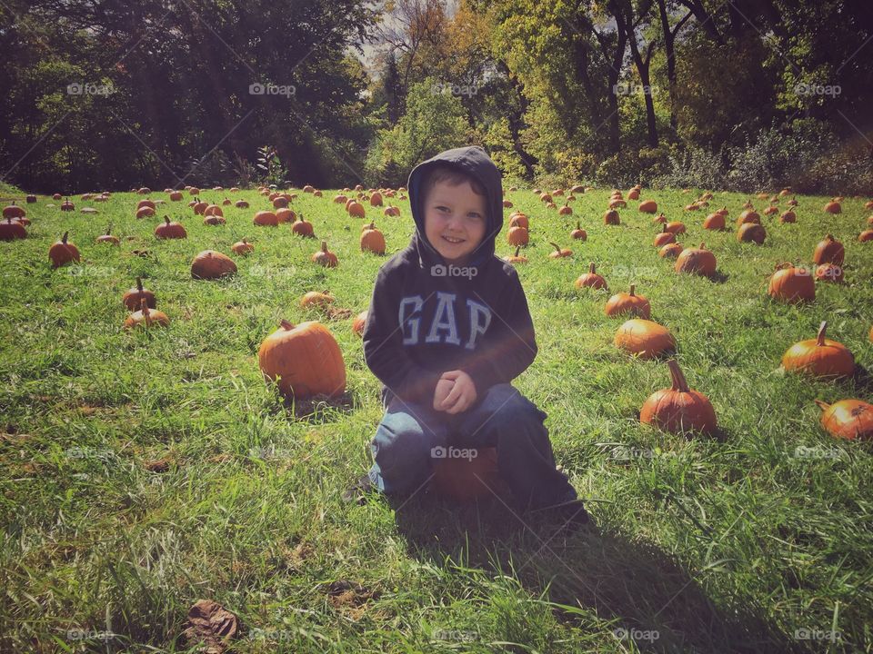 Boy sitting on pumpkin