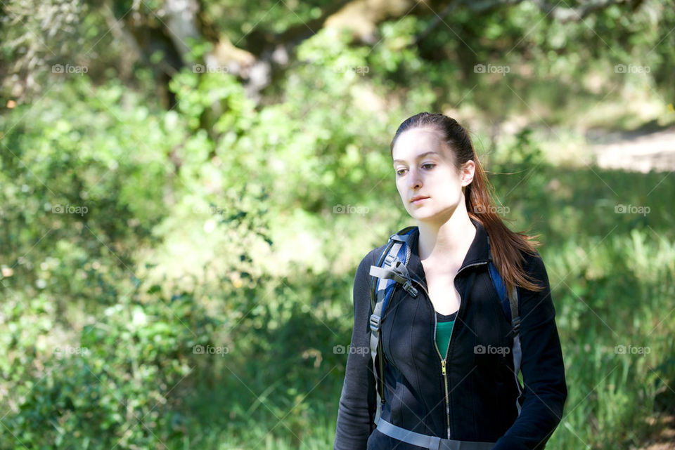YOUNG WOMAN HIKES THROUGH A FOREST