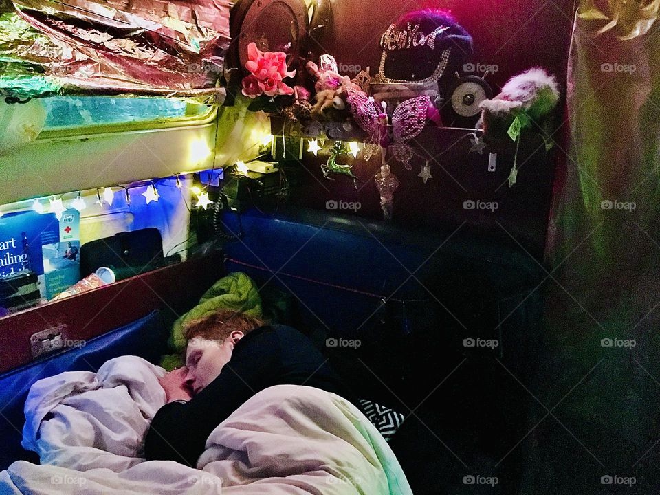 Sleeping peacefully below the starry lights of the Christmas decorations I am safely aboard our first boat, “Salvation #1”. 2017. Hypnotic Productions