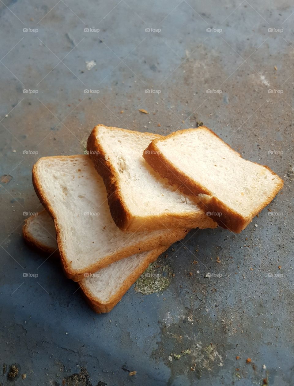 Four slices of white flour bread on blue background