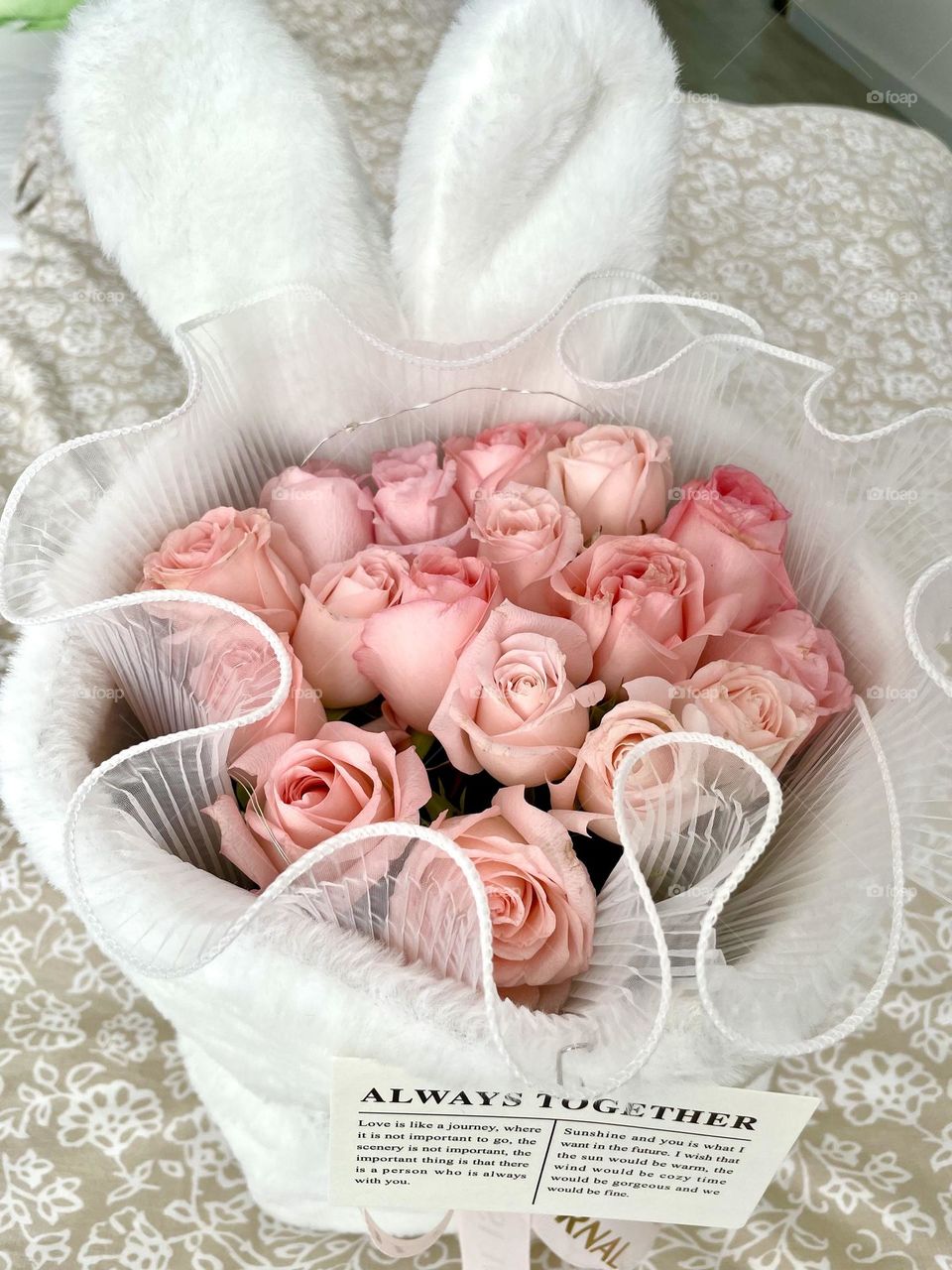 Bunch of open baby pink roses in white covering on bed
