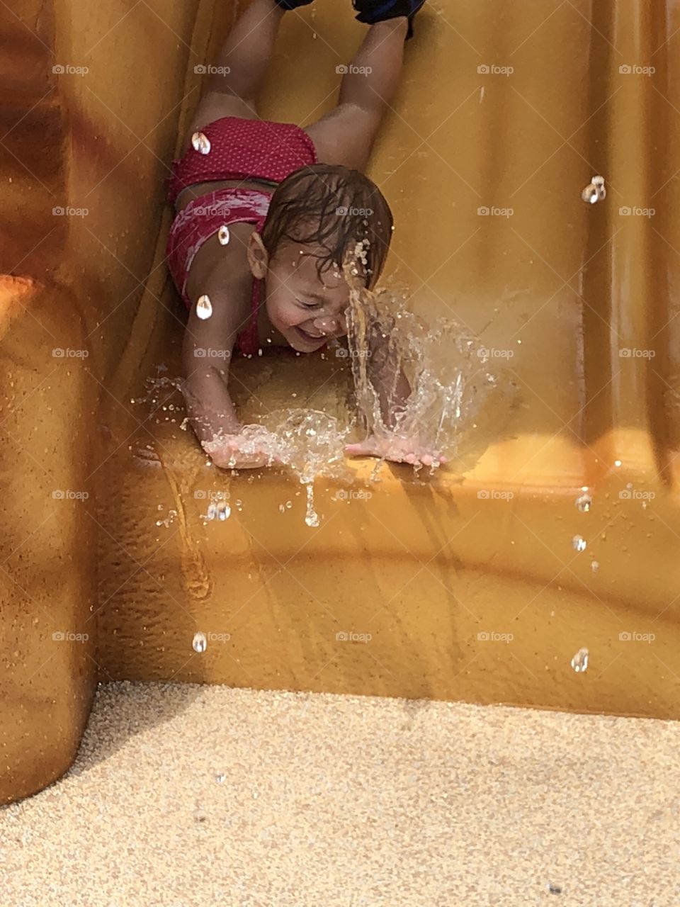 Toddler girl going head first down a water slide