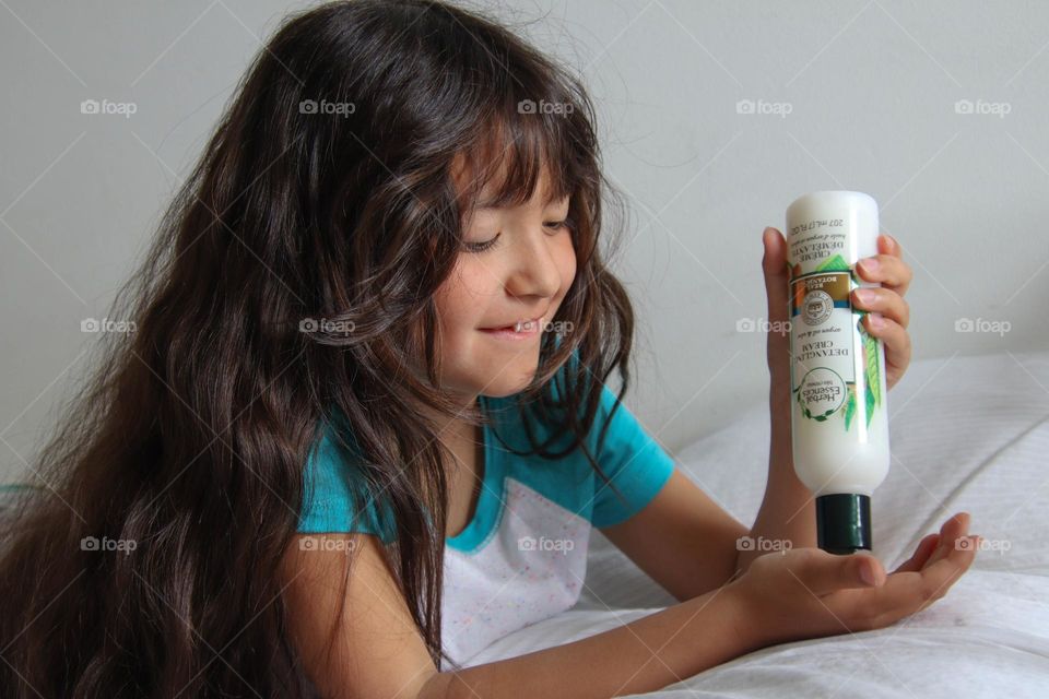 Cute little girl using Herbal Essences detangling cream