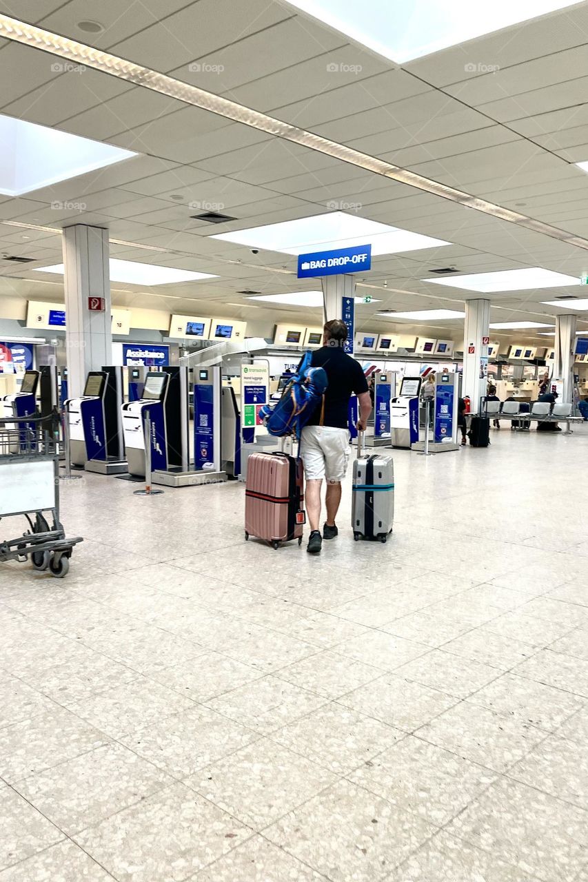 Man with his bags going towards the check in disk at the airport 