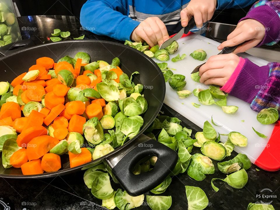 Kids prep food cutting vegetables carrots brussel sprouts 
