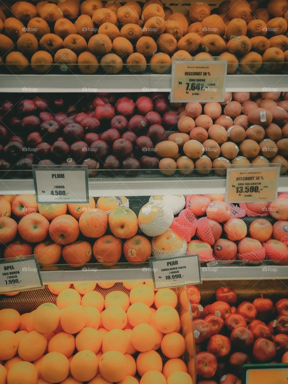 Portrait of various types of fruit neatly arranged on a shop display shelf