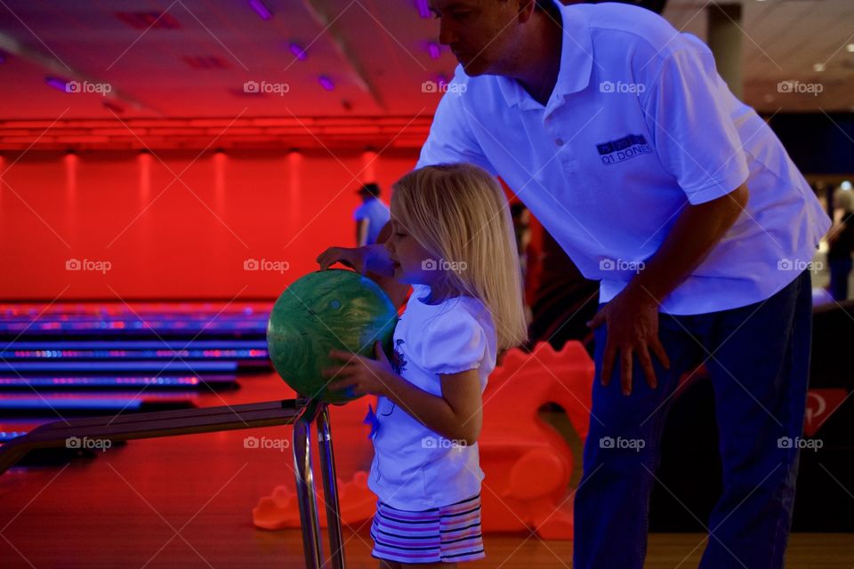 Dad teaching his daughter to bowl 