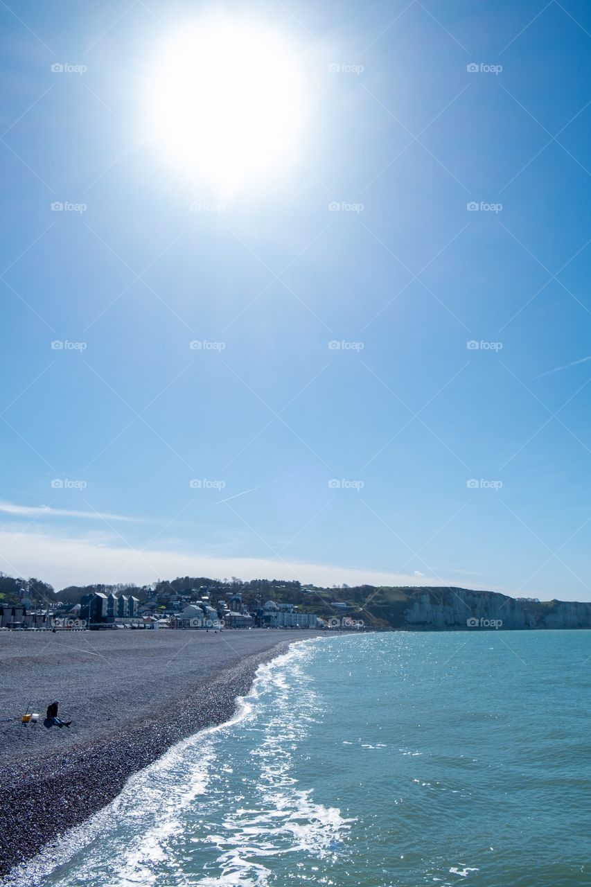 The Pebble beach and Hite chalk cliffs of the Normandy coast under the sunny blue sky