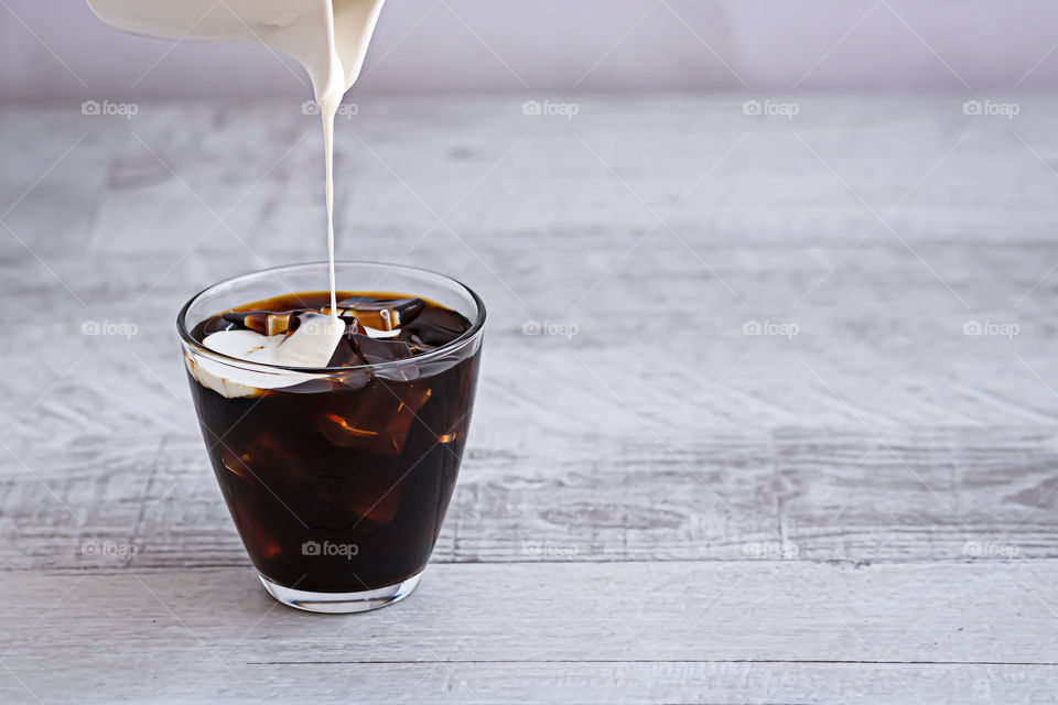 Cream pouring in the glasses with coffee.