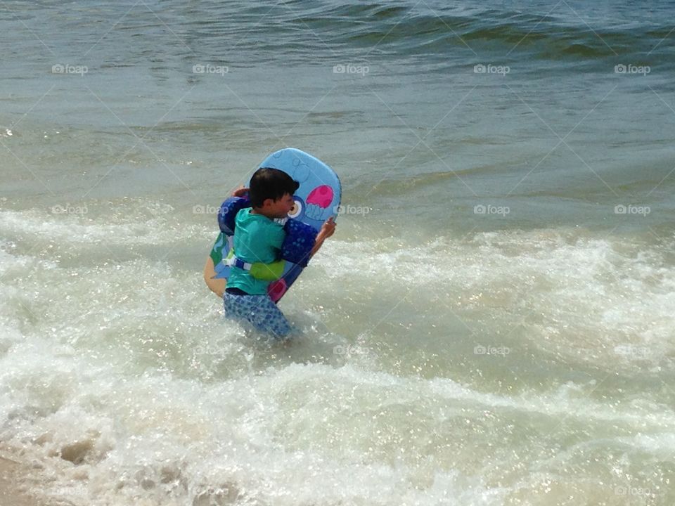 Boy holding bodyboard in the sea