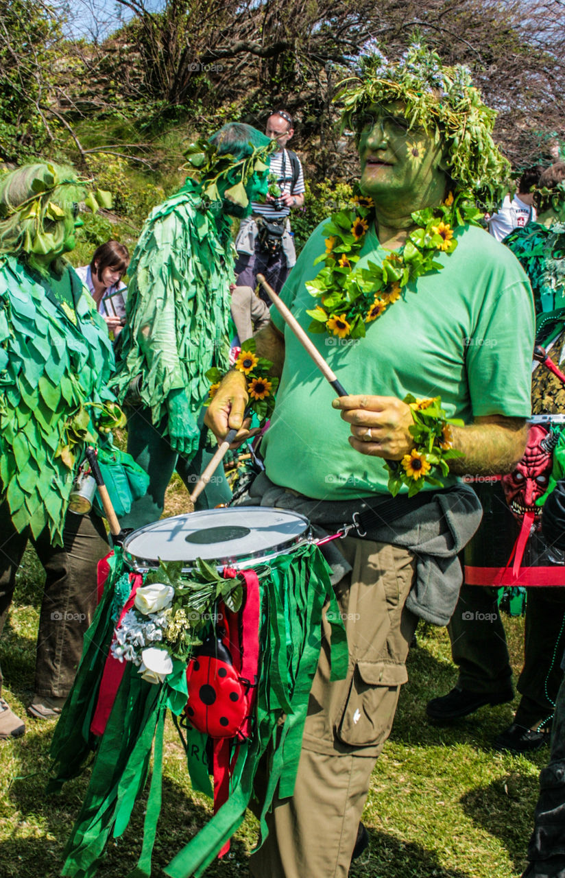 A man draped in sunflowers and wearing green, plays a drum at Hastings Traditional Jack in the Green, U.K. 2008