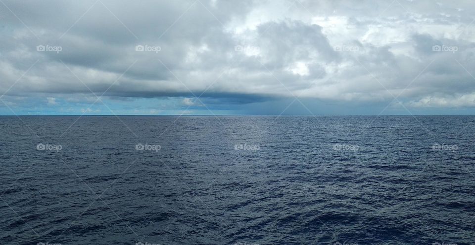 The view of the sky between thick clouds and blue sea.