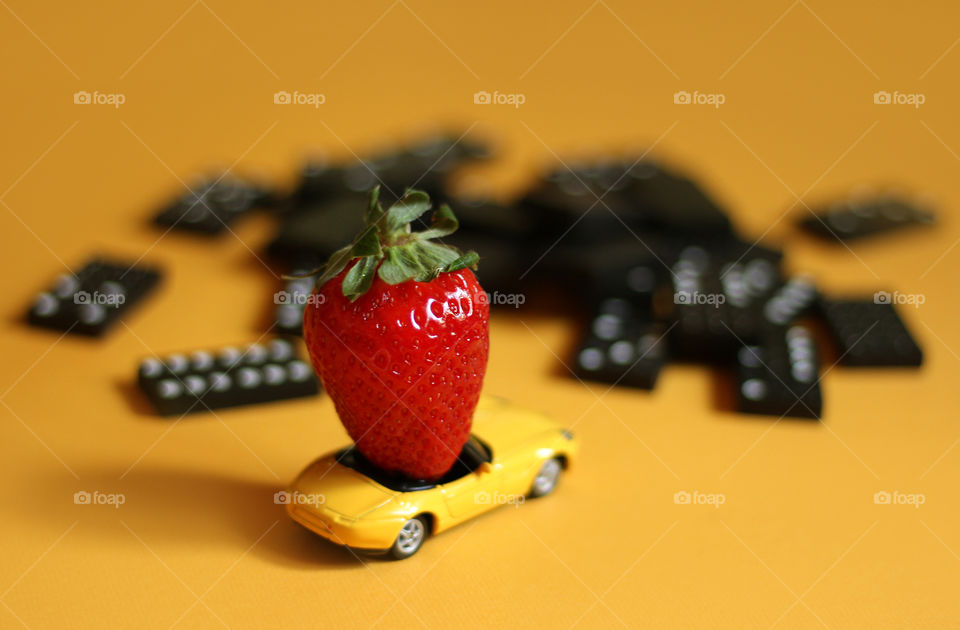 It's time to travel, strawberry in the toy car, domino pieces on the background