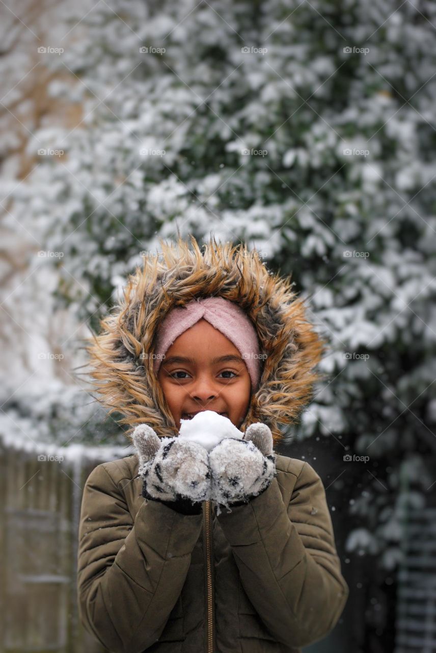 Girl of mixed race holding a snow ball in snow ball fight