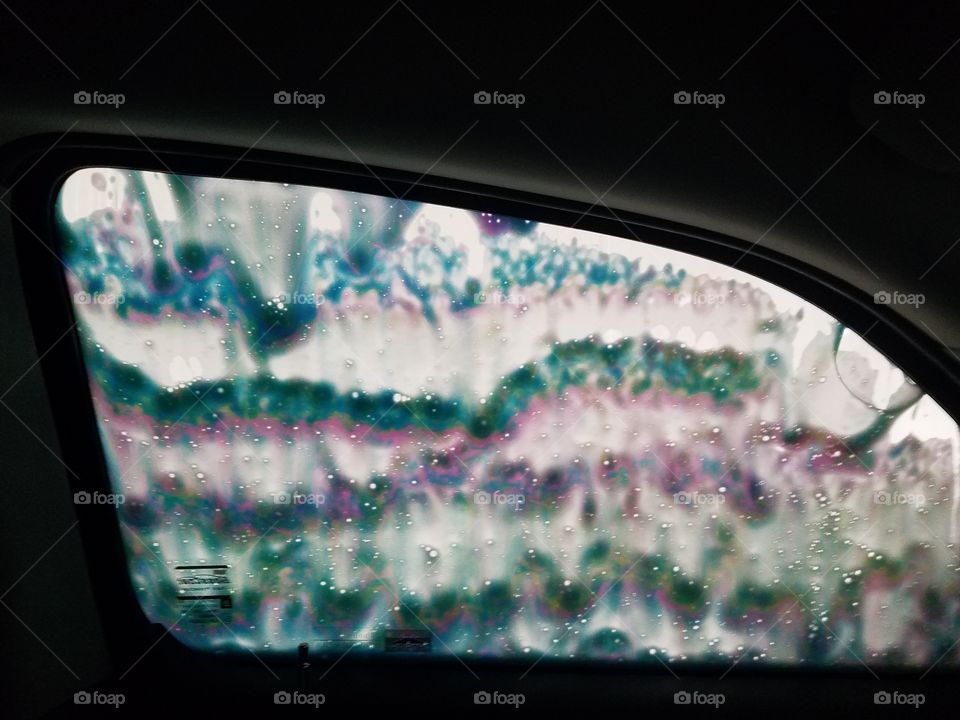 Tie-dye rainbow hippie soap on car window at laser car wash.