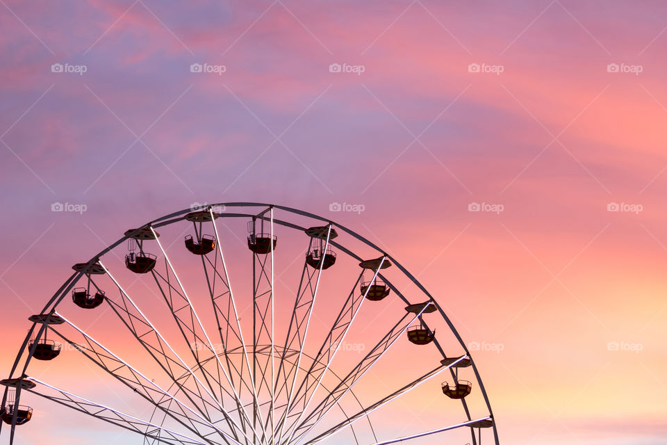 Colorful pink sunset against silhouetted giant ferris wheel