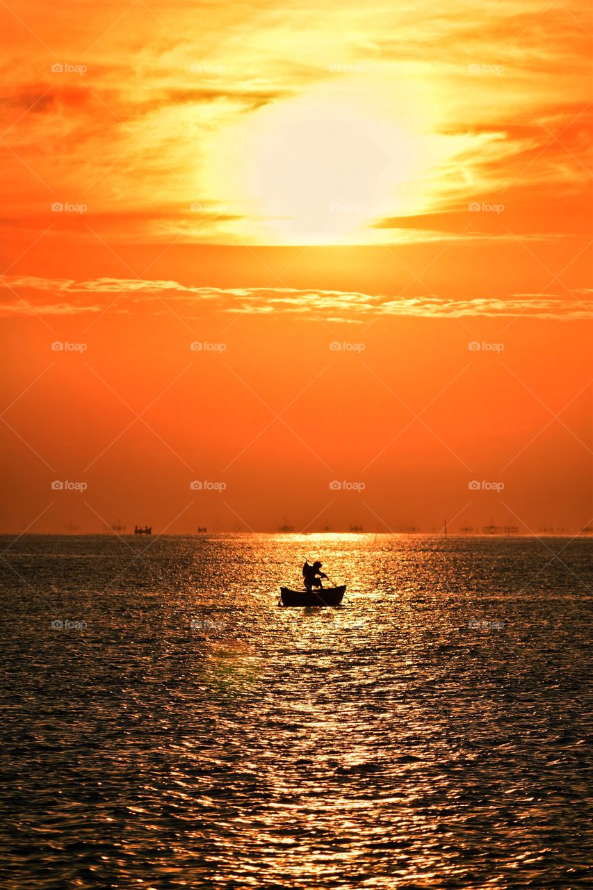 a fisherman is looking for fish when the sunrise.
