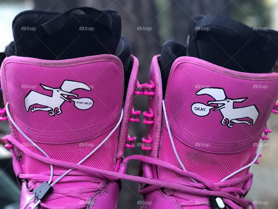 A closeup of the graphics on a bright pink pair of used and worn snowboard boots. 