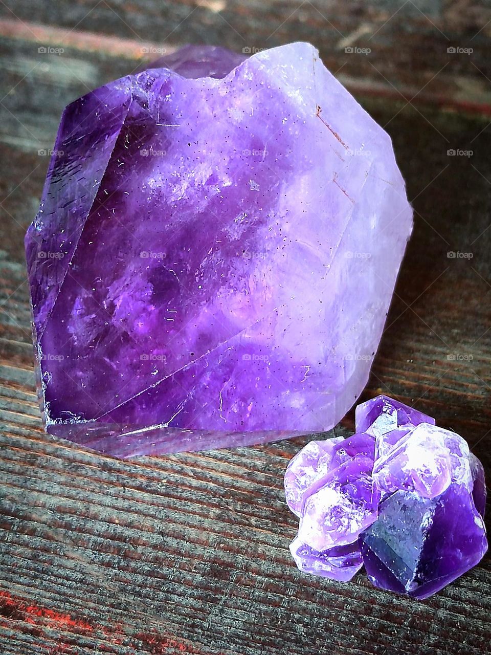 Lavender. Two uncut lavender amethysts lie on a wooden background. Amethysts vary in shape and size