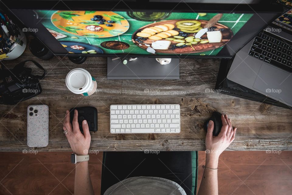 Image of a woman working at a computer desk from above 