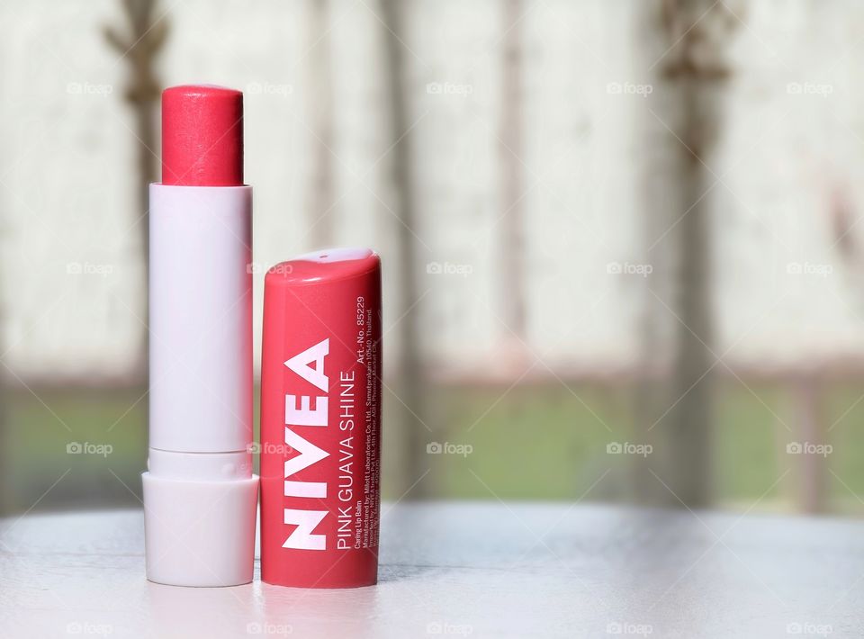 NIVEA Pink guava Shine Lip Color Lipstick With Blurred Curtain Background.