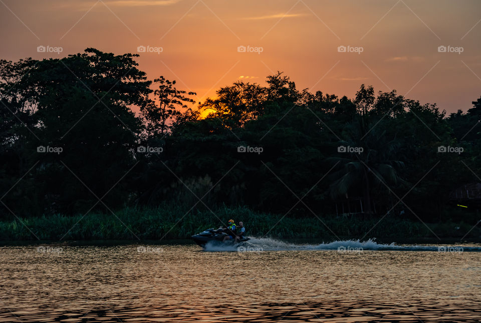 Tourists drive the Jet Ski and the sunset light in Khwae Noi river at Kanchanaburi Thailand .December 2, 2018