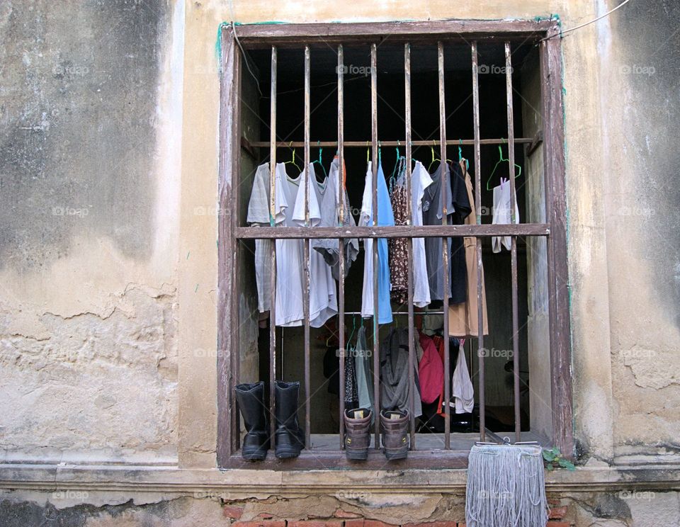 Colorful wet cloths hang along with boots and a mop, can be viewed from a street level window in Bangkok, Thailand 
