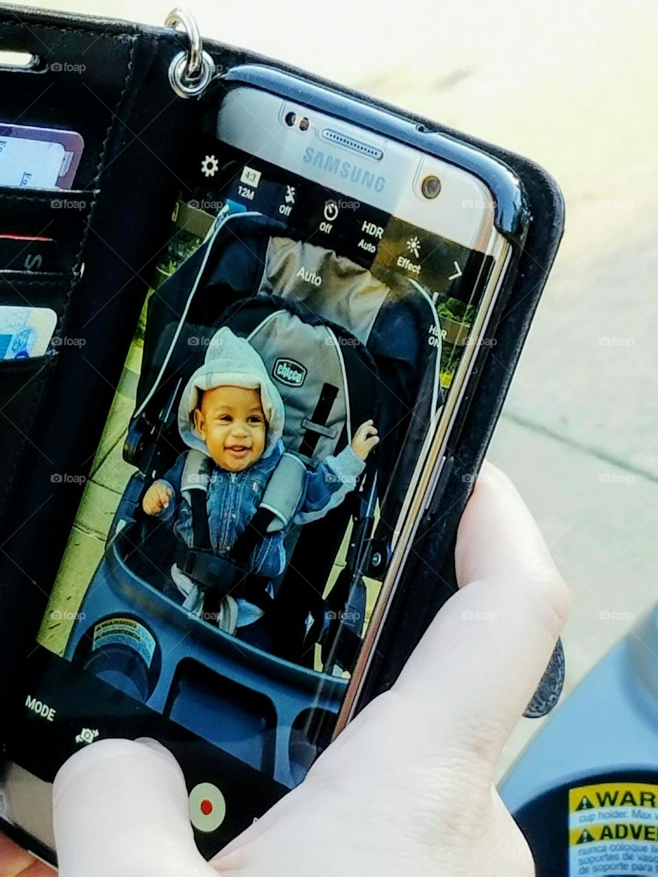 Mother taking photograph of her baby boy sitting in stroller