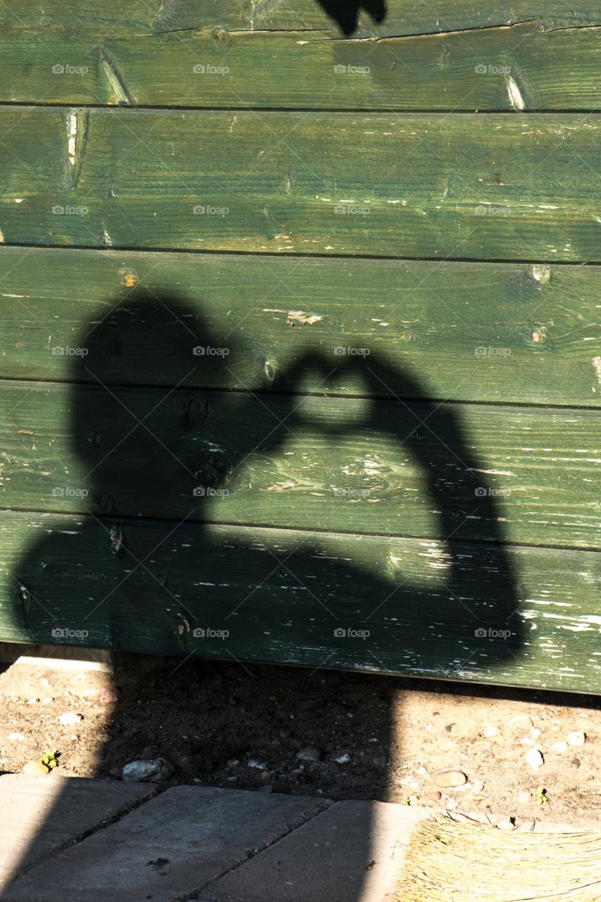 Girl making a heart shape on the wall with her shadow