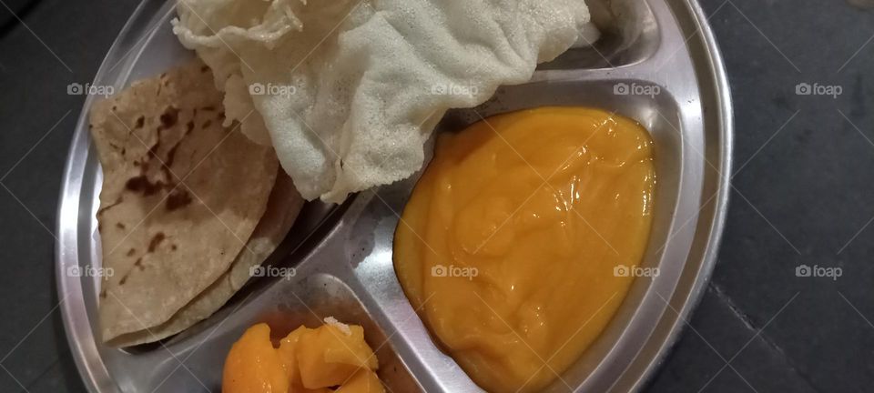 Season's special thali mango puree with gram been flour papad and wheat flour's chapati or poli. Very popular dish.