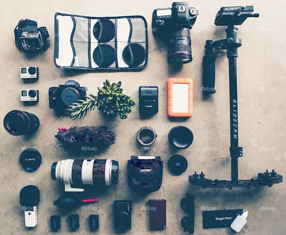 Camera and Accessories.
Overhead view of different types of cameras with lenses and tripod.