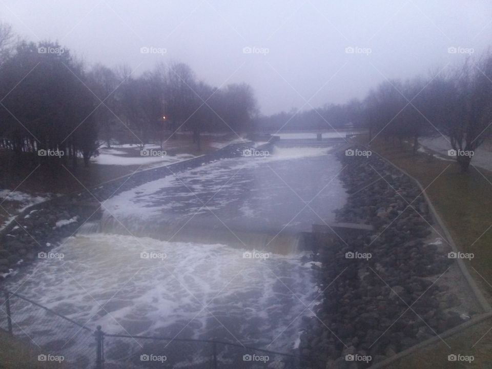 The Manitowoc River flowing rapidly through two dams on a rainy first day of Spring early evening in Chilton, Wisconsin 35 miles South of Green Bay.