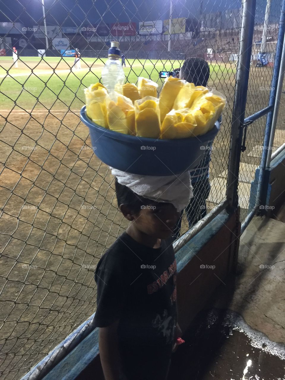 Young boy selling mango slices at baseball game in Managua. 