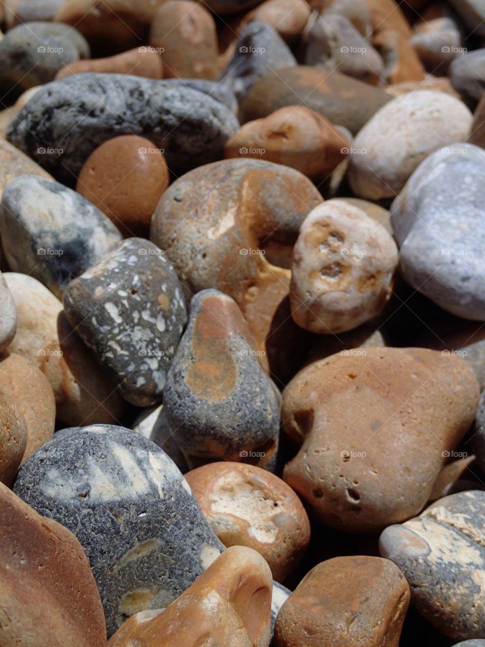 Closeup of smooth rocks from unlimited years of wearing on the rocky European beaches on a sunny summer day. 
