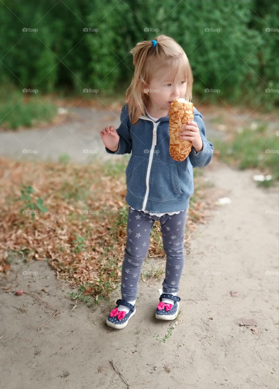 Little cute girl eating a bun