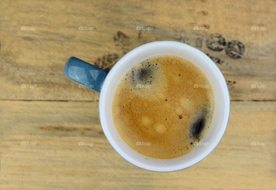 blue cup of coffee on a wooden background with coffee bean stamp