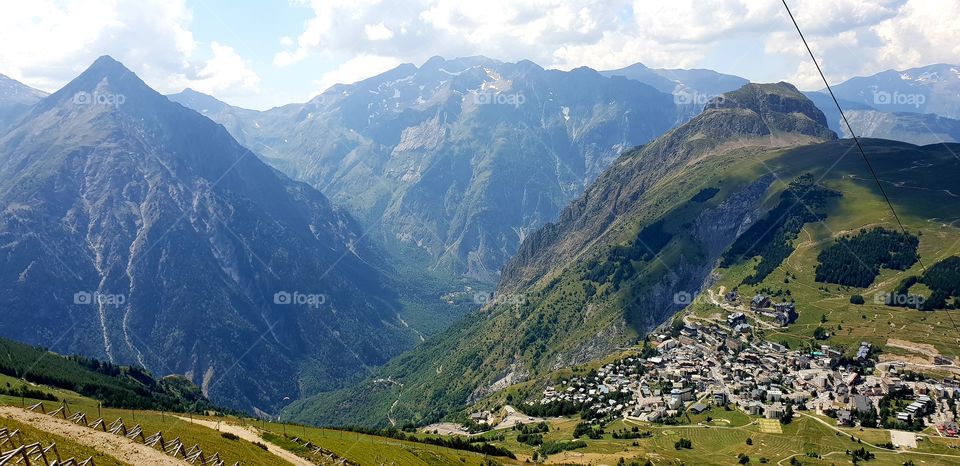 View from the french alps on a mountain and a little village below with blue sky and some cloud