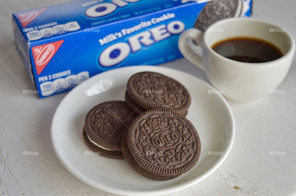 A flat lay of Oreo cookies on a plate and a cup of coffee