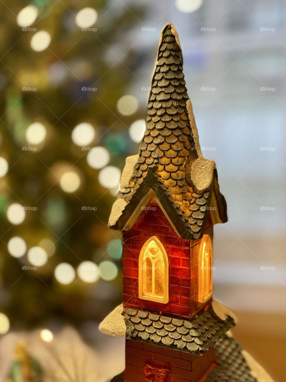 Church steeple tower with windows alight at Christmas, Christmas tree lights Bokeh blurred background, room for copy text. 