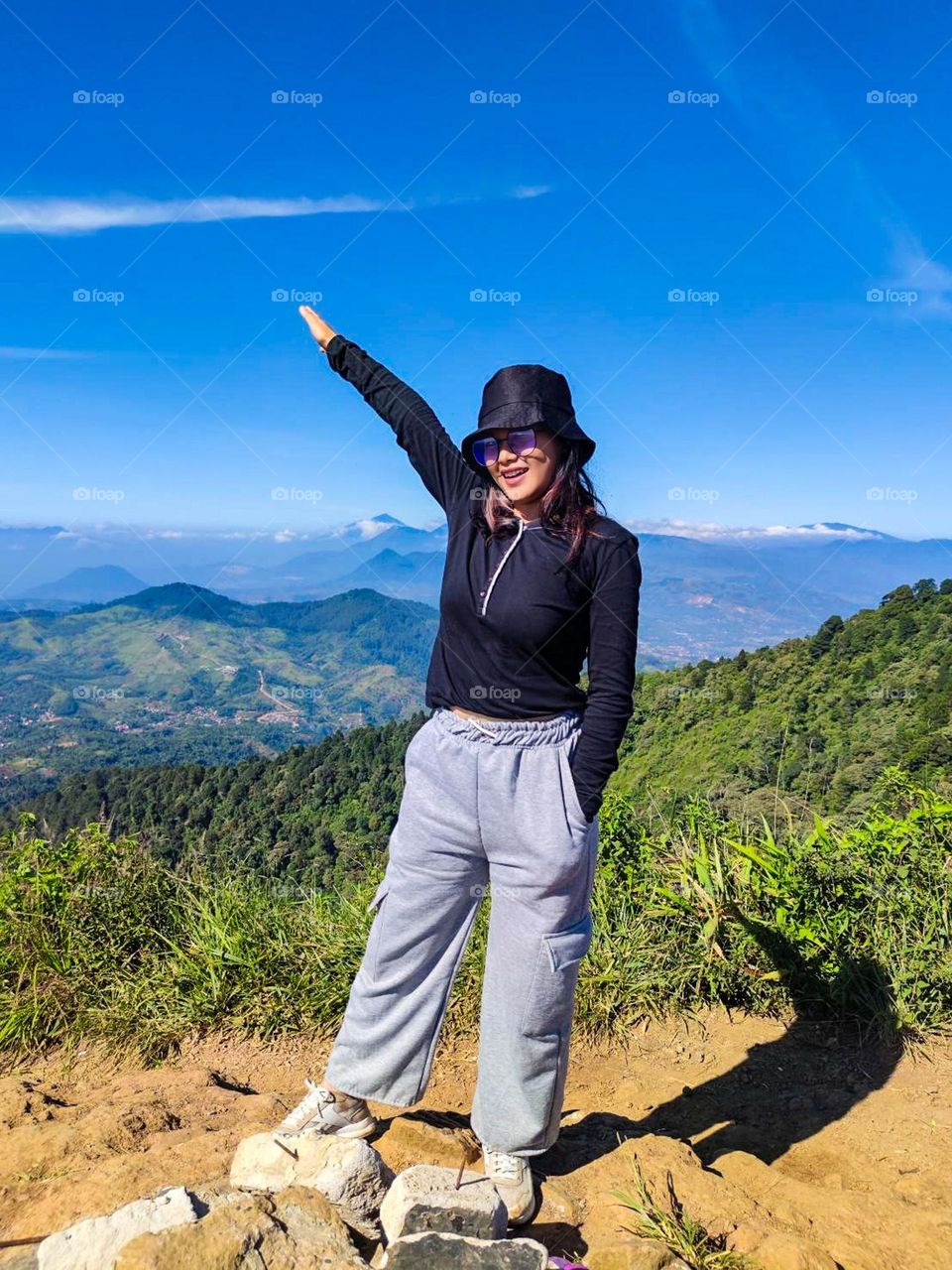 Full length of woman standing on mountain against blue sky