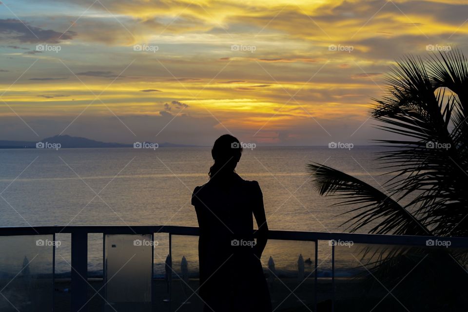 Girl watching sunset on beach in tropics