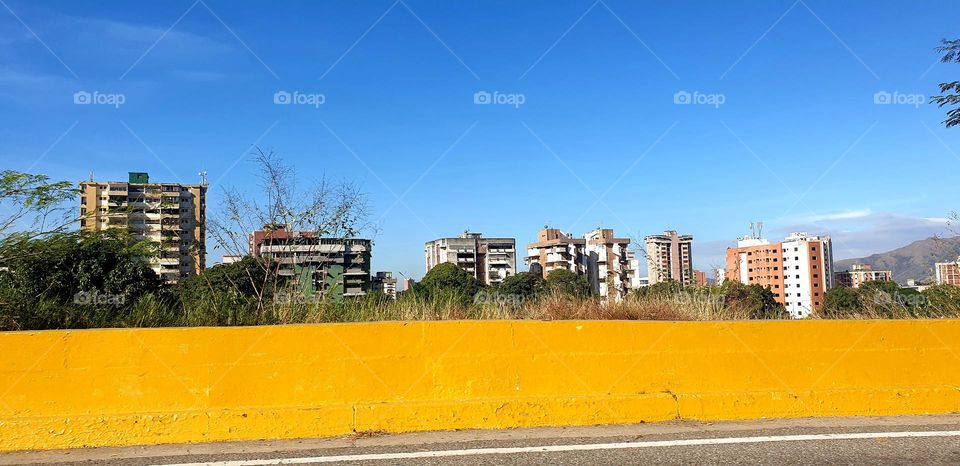 going up the road and see the blue sky looking at the city and the yellow band of cement that limits is space