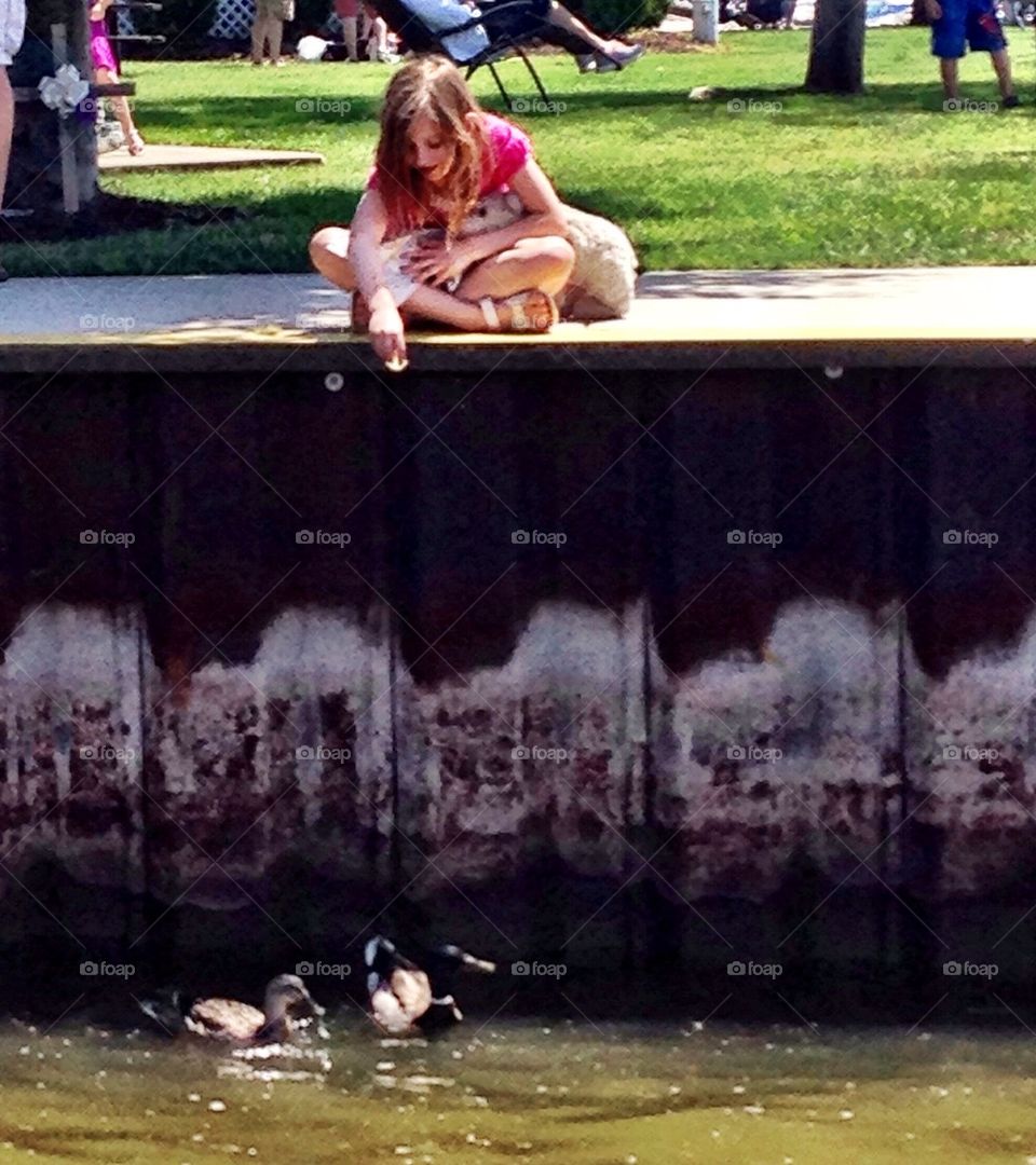 A little girl and her Teddy feeding the ducks. 
