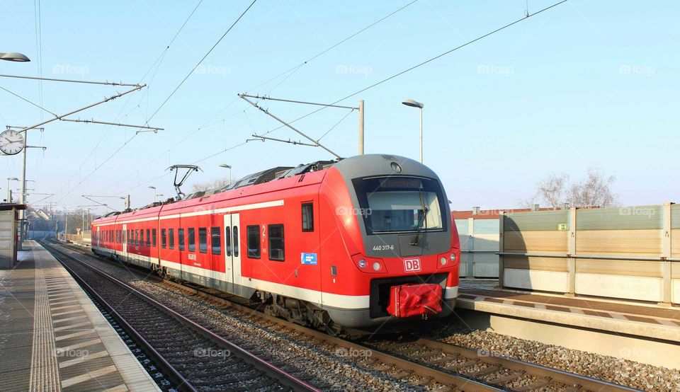 red train at a little  railway station