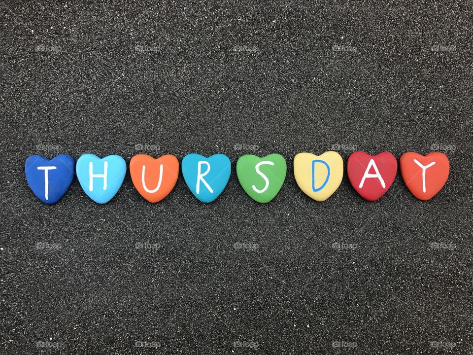 Thursday, day of the week with multicolored heart stones over black volcanic sand 