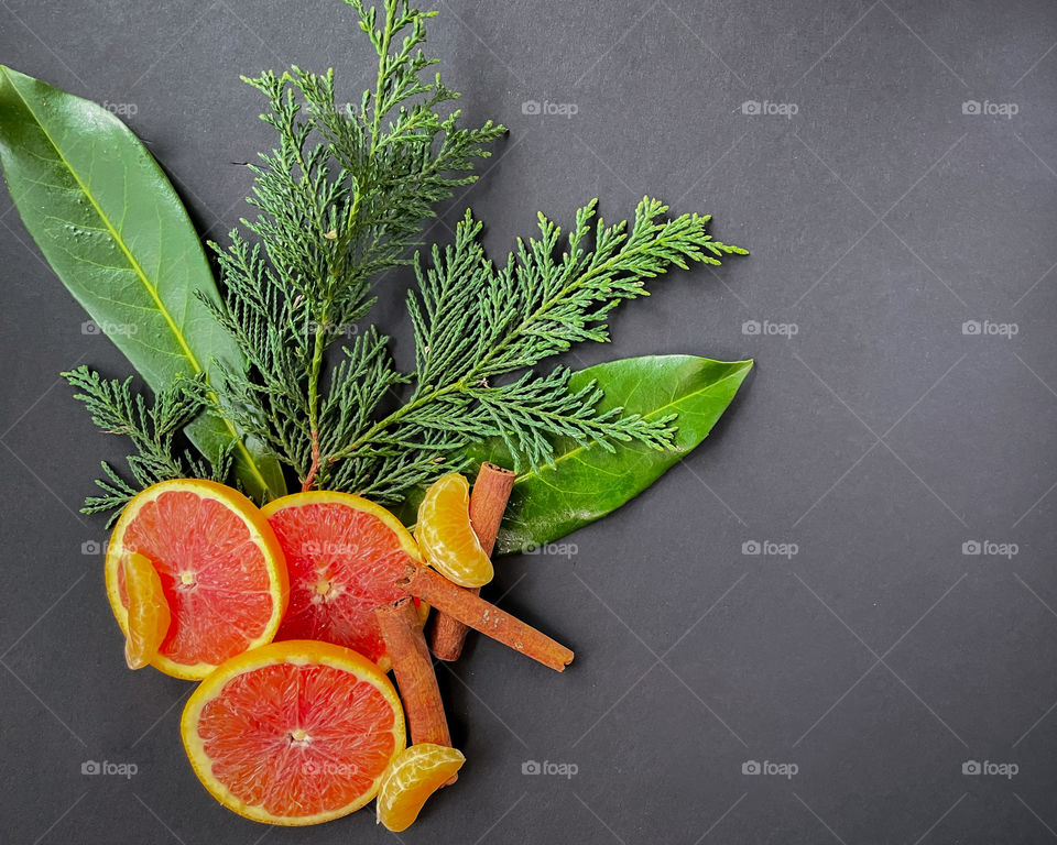 Three orange slices, cinnamon sticks, mandarin orange segments and leaf sprigs. 