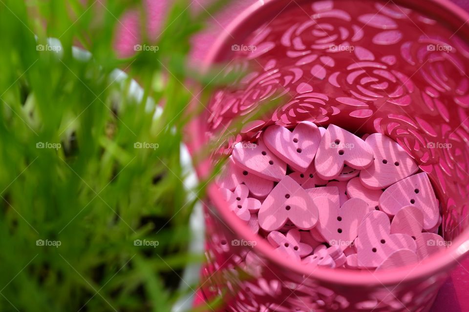 pink color wooden buttons hearts and flowers green grass background