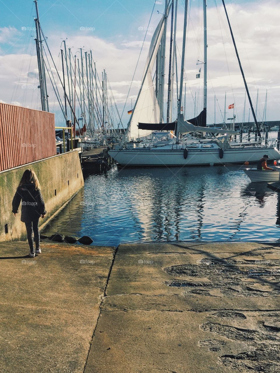 A girl walking in the harbor full of sailingboats